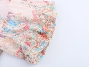 Detail of floral chiffon fabric with delicate white embroidery and puff sleeve texture