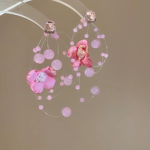 Close-up of pink fabric flower earrings with resin beads and sparkling crystal studs