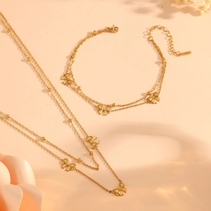 Set collana e bracciale a doppio strato con fiocchi dorati e perline su sfondo beige