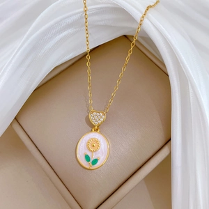 Macro shot of gold sunflower necklace with white enamel shell on a beige velvet jewelry box