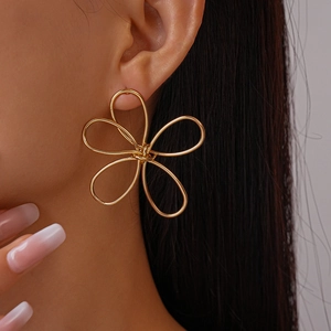 Close-up of golden hollow twisted flower earring worn by model for elegant style