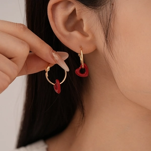 Close-up of model wearing vintage red heart drop earrings with gold metal rings
