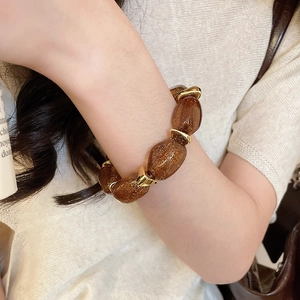 Close-up of amber acrylic beaded bracelet with golden spacers on a model's wrist