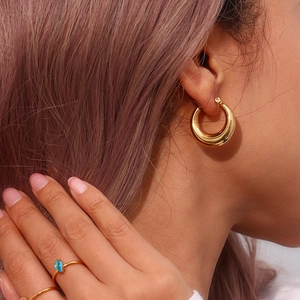 Detail of 25mm 18K gold plated chunky hoop earrings worn with matching gold rings
