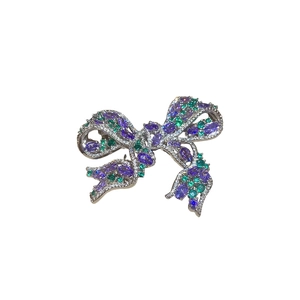 French luxury zircon bow brooch with purple and green stones on a silver metal base