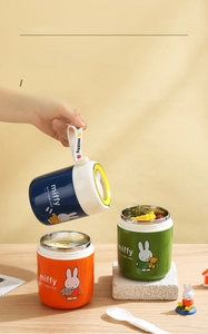 Three colorful Miffy stainless steel soup cups with silicone handles on a wooden table