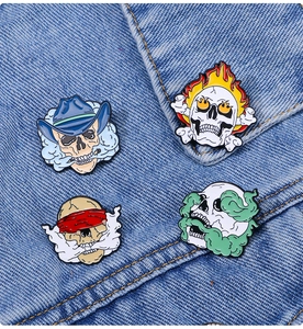 Detail of dark punk skull enamel pins with flame and cowboy motifs on denim jacket
