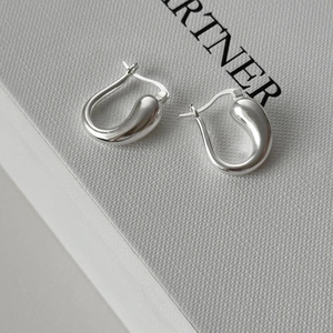 Macro shot of silver teardrop hoop earrings with polished mirror finish on textured box