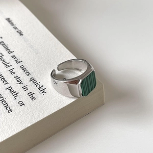 Minimalist 925 sterling silver open ring with square green malachite stone on a book