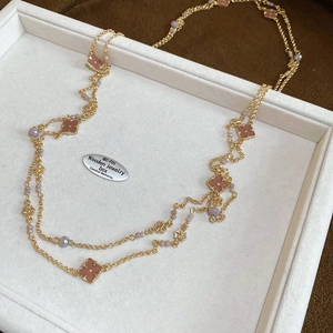 Detail of French vintage necklace featuring enamel clovers and purple beads on a gold chain