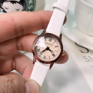 Close-up of rose gold quartz watch with white leather strap and Roman numeral dial