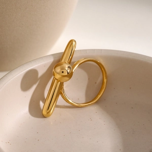 Nahaufnahme eines goldenen geometrischen Rings mit Kugel und Stab auf Keramik