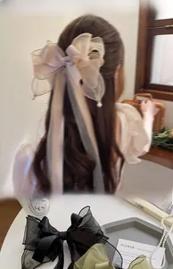 Detail of oversized organza bow hair clip with long ribbons and elegant pearl pendants