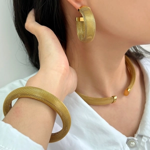 Close-up of golden mesh texture on the minimalist C-shaped jewelry set worn by model