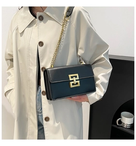 Détail d'un sac bandoulière noir plissé avec fermoir doré et bandoulière chaîne