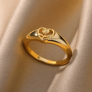 Macro detail of gold flower ring with sunflower heart design on soft beige silk background