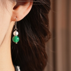 Dettaglio dell'orecchino vintage con perla bianca e agata verde indossato dal modello