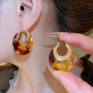 Detailed shot of amber acetate resin C-hoop earrings with gold-toned metal inlay