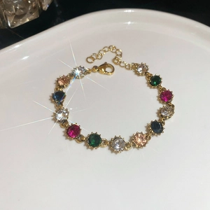French palace style gold chain bracelet with colorful zircons in a white ceramic bowl