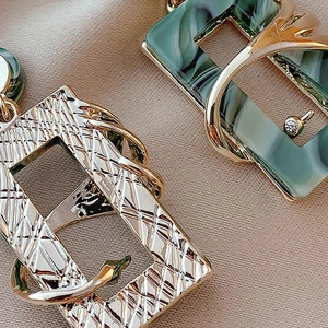 Macro shot of vintage green acrylic earrings with embossed gold-tone metal and marble texture
