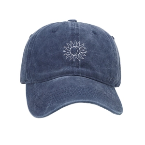 Detailed close-up of white sunburst embroidery on washed navy cotton baseball cap