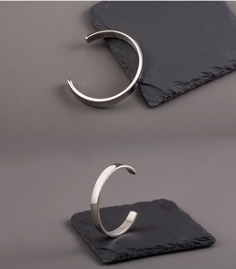 Polished 8mm stainless steel open C-shape oval bracelet on dark stone background