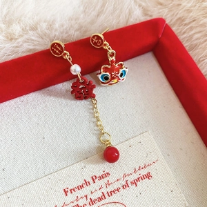 Détail de boucles d'oreilles pompons rouges avec motifs de danse du lion et caractères