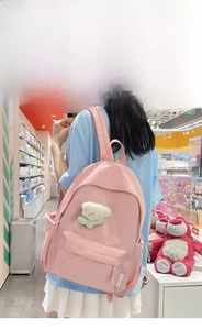 Pink minimalist nylon backpack with plush bear charm and fashion logo shown on model