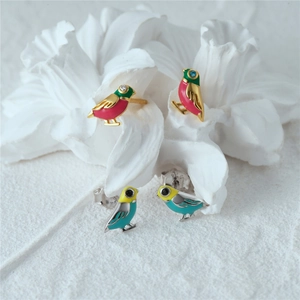 Detail view of colorful bird stud earrings with enamel and crystals on ceramic flower
