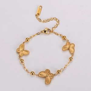 Détail macro du bracelet papillon doré avec gravure 18KGP sur l'étiquette en métal poli