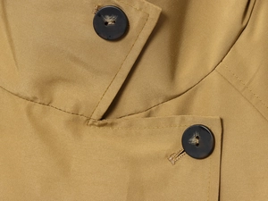Detailed close-up of khaki cotton trench coat fabric with marble-textured brown buttons