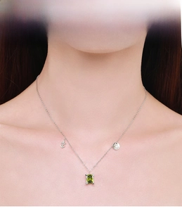 Detail of S925 silver necklace featuring emerald cut green gemstone and star charms