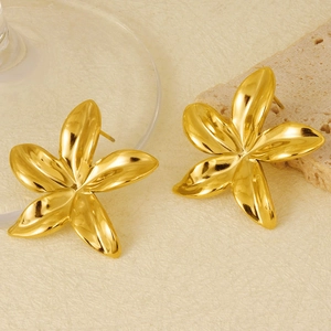 Vue détaillée de boucles d'oreilles fleurs en or 18k sur fond de pierre naturelle