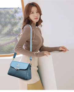 Detail of blue textured woven leather handbag with golden floral clasp and logo