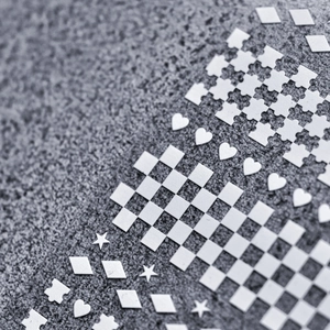 Macro detail of white checkerboard and geometric nail art stickers on a matte grey base