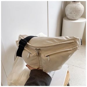 Detail view of beige crossbody bag with multi-zipper pockets and adjustable wide black strap