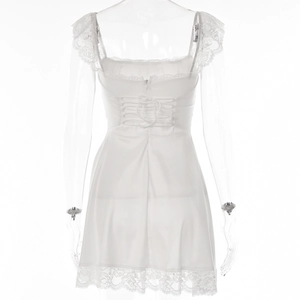 Detail of white backless mini dress featuring lace trim and adjustable lace-up tie closure