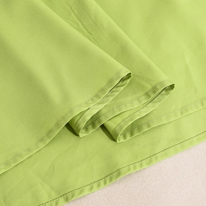 Detailed macro view of bright green fabric with precise double-needle stitching quality