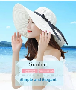 Detail of a white woven beach sunhat featuring an elegant wide brim and black ribbon bow