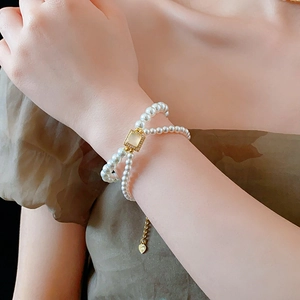 Detail of 18k gold plated double-layer pearl bracelet with square gemstone on wrist