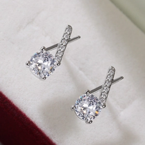 Macro detail of silver X-shaped earrings with round zircon and micro-pave crystals