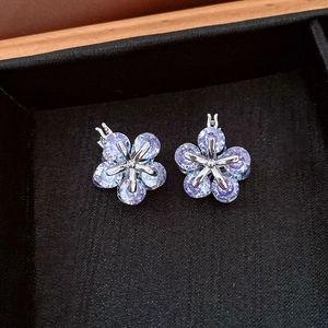 Détail des boucles d'oreilles fleur en argent avec zircons violets sur velours noir