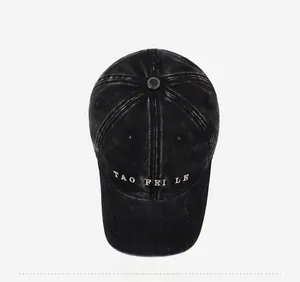 Top view of a washed black baseball cap featuring white letter embroidery and retro finish