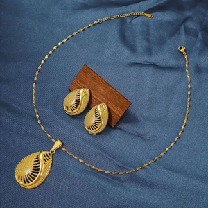 Macro detail of gold waterdrop hollow earrings and necklace on dark textured wood