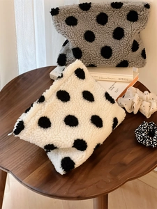 Detailed macro view of soft polka dot faux shearling pouches on a rustic wooden table