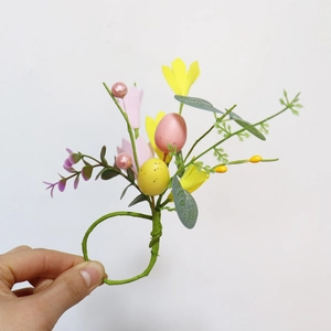 Close-up of Easter napkin ring with colorful eggs, yellow flowers, and pearls on green vine