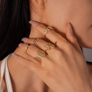 Detail view of gold starfish and shell rings with metallic texture on model hand