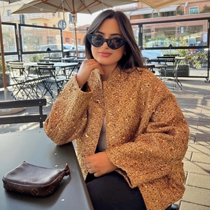 Golden sequin tweed jacket for women featuring a stand collar in an outdoor cafe setting