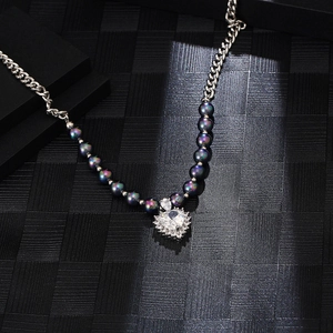 Macro detail of silver titanium chain with colorful pearls and zircon heart pendant