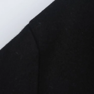 Close-up of high-quality black wool fabric showing shoulder seam detail on a winter coat